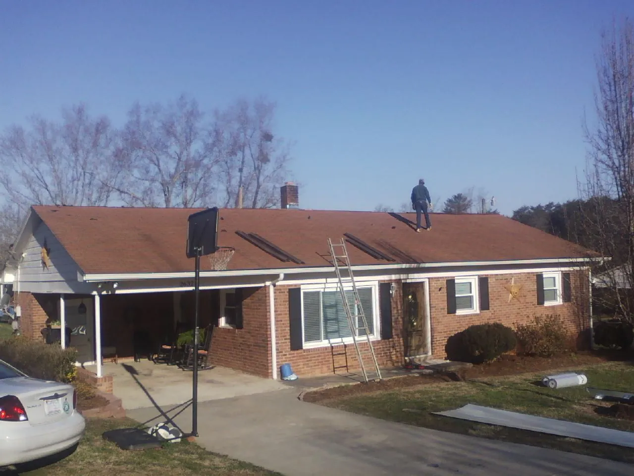 Roofer stripping a shingle roof on a brick ranch before metal panels in Brownsville
